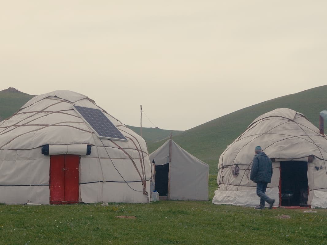 Le camp de yourtes d'Azamat, deux yourtes blanches à porte rouge au pied des collines